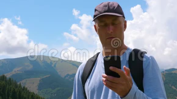在山区景观中使用手机的成年男子低视角视频的预览图