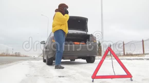 冬季驾驶汽车故障紧急信号在下雪的乡间小路上遇到了汽车故障一位年轻女子呼叫救援视频的预览图