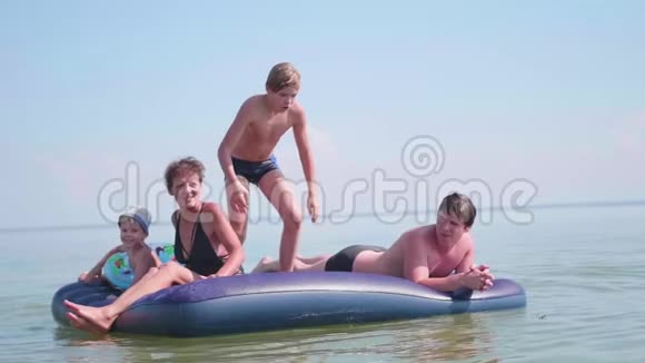 一家人在一个大充气床垫上在海里游泳快乐的童年积极正面视频的预览图