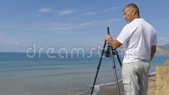 录像员用三脚架上的摄像机拍摄海岸视频的预览图