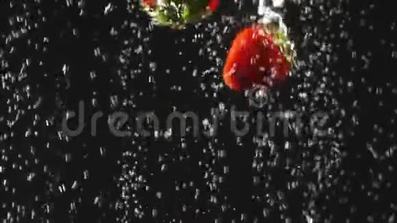 落下来的新鲜草莓和樱桃溅到闪闪发光的水在黑色的背景特写镜头视频的预览图