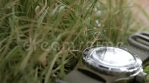 特写在绿草地上躺着一只潜水表强调红色秒针在黑色上的移动视频的预览图