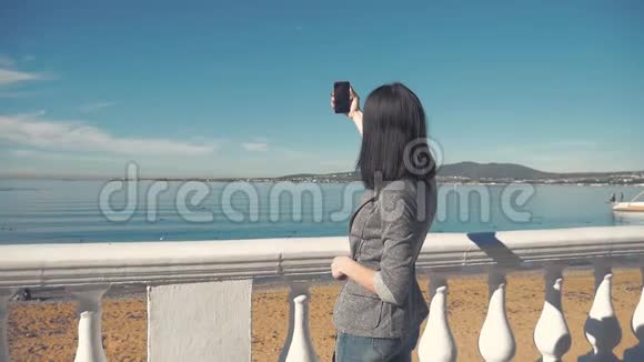 在海滩的地平线上一位女士用智能手机相机拍照年轻女孩拍照视频的预览图