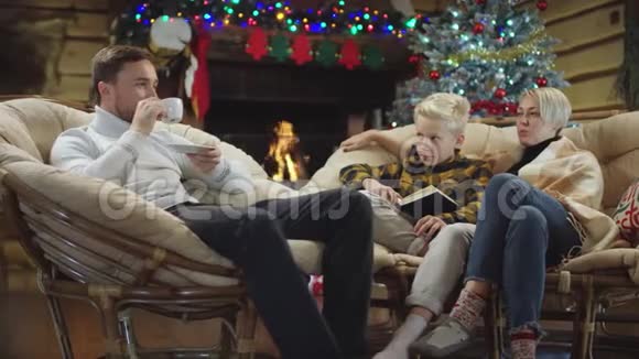 成年男子与妻子和儿子在圣诞节晚上用书交谈视频的预览图