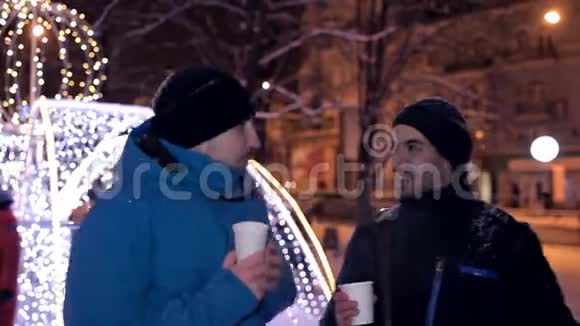冬天的晚上两个人在公园里喝咖啡在美丽的圣诞装饰附近视频的预览图
