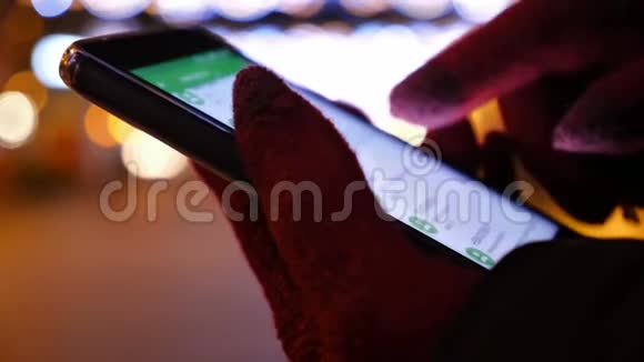 戴手套的女人在冬天的城市处理智能手机视频的预览图