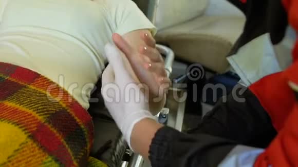 女性患者躺在担架上握住男性护理人员的手救护车视频的预览图