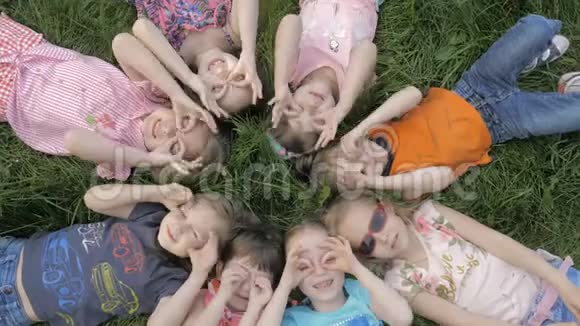 一群幼儿园的孩子躺在公园的草地上微笑着放松视频的预览图