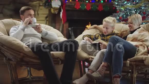 男人喝咖啡而小男孩在圣诞夜看书视频的预览图
