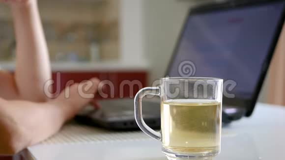 桌子上有一杯茶后面是一台笔记本电脑女孩们的手触摸手提电脑的钥匙视频的预览图
