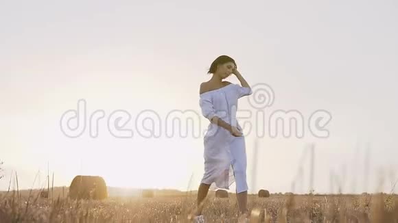 一个年轻的女孩跑在田野里在日落的一个夏天的晚上绕着他转圈一个漂亮的女孩视频的预览图