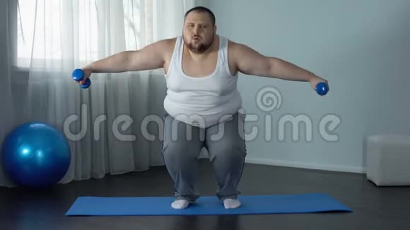 精疲力竭的胖子坐在地板上戴着哑铃疲惫的锻炼计划运动视频的预览图