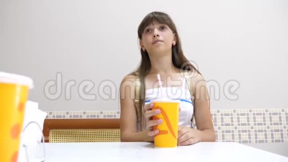美丽的女孩坐在咖啡馆的桌子旁喝着鸡尾酒微笑着视频的预览图