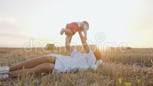 年轻的妈妈躺在地上戴着草包的围巾和快乐可爱的小男孩玩耍妈妈抱着视频的预览图