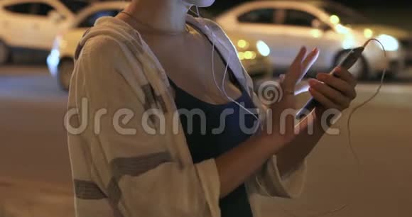一个女人晚上在城里用手机的手视频的预览图