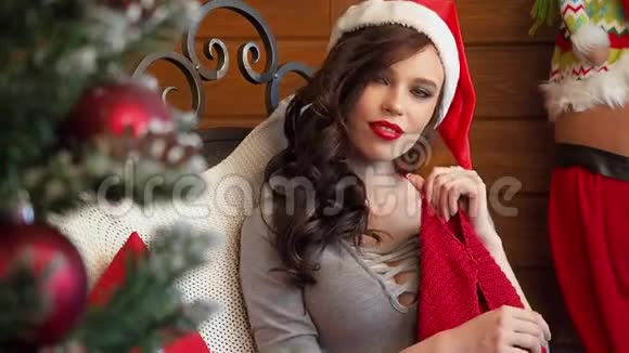 带着圣诞帽的女孩用圣诞礼物包许愿假期和新年的概念女孩很高兴视频的预览图