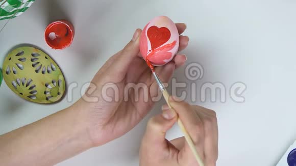 女人用画笔在鸡蛋上画红色图案手工装饰创意视频的预览图