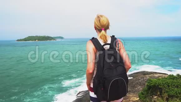带背包的女孩沿着亚洲海岸旅行站在海滨远远望着地平线上的岛屿视频的预览图