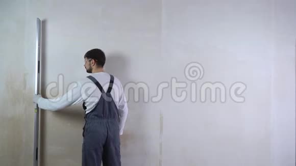 男建设者检查新墙的平整度气泡水平面有自由空间视频的预览图