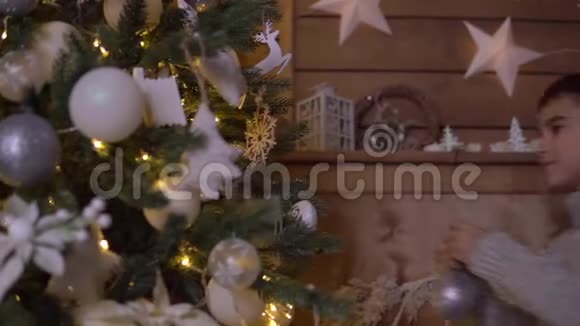 一个小男孩用一个漂亮的球装饰一棵圣诞树视频的预览图