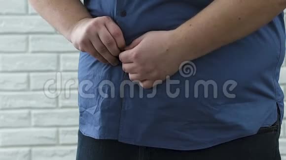 一个胖男人很难在大肚子上扣上扣子加上尺寸不安全视频的预览图