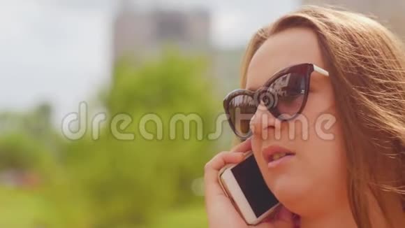 带着眼镜的年轻女人在街上打电话近距离射击视频的预览图