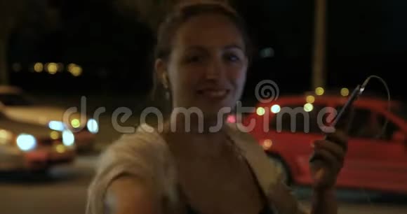 一个女人晚上在城里用手机的手视频的预览图