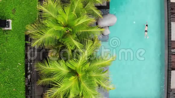在绿色的豪华游泳池附近的米色比基尼放松和日光浴的无法辨认的苗条年轻女性的俯视图视频的预览图
