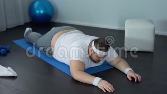 胖乎乎的男人在家里加强背部肌肉静态锻炼力量视频的预览图