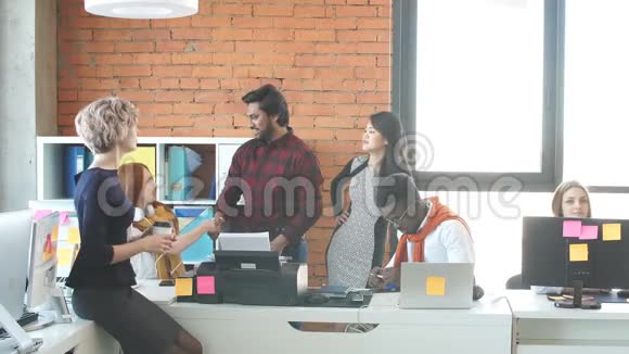 印度教的家伙正在和坐着的红发女人握手用手中的咖啡问候金发女人视频的预览图