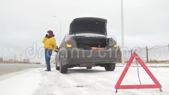 汽车故障紧急信号在下雪的乡间小路上遇到了汽车故障一位年轻女子呼叫救援服务视频的预览图