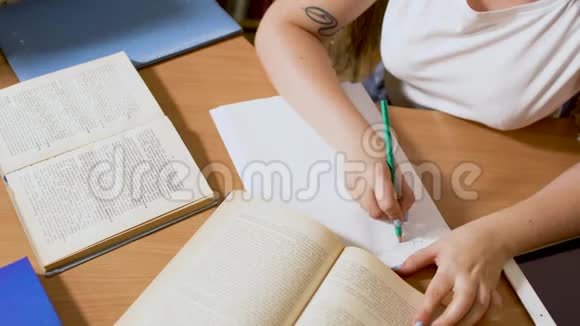 女孩正在桌旁用铅笔写字视频的预览图