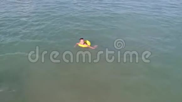 一个活泼的小男孩漂浮在蓝色的海水中视频的预览图