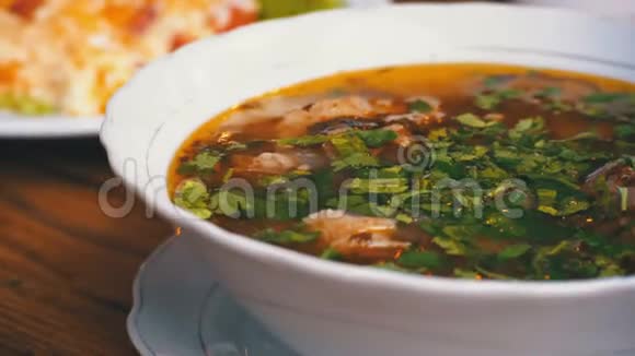 木制餐桌上的格鲁吉亚传统哈什拉马汤和西红柿汤视频的预览图