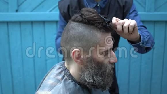 女理发师做时髦男理发师用电动剃须刀和梳子在户外理发店理发视频的预览图