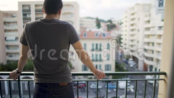 在辛苦工作的一天之后男性站在阳台上欣赏街景视频的预览图