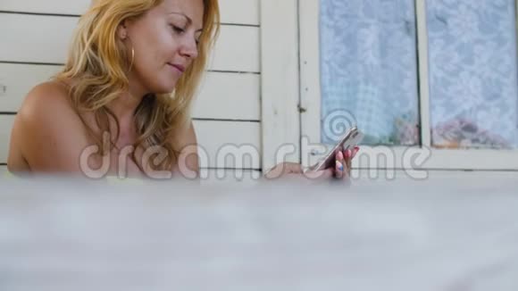 成年妇女在夏季住宅室外露台充电时使用手机视频的预览图