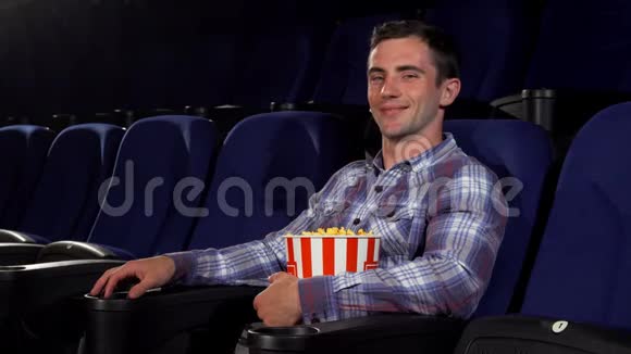 快乐英俊的男人开心地笑着坐在电影院视频的预览图