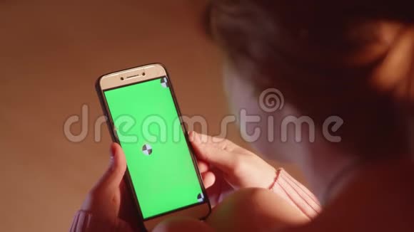背面的女孩持有智能手机与绿色屏幕和跟踪点和手势视频的预览图