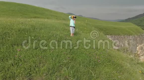 这位戴着眼镜和帽子的女摄影师在靠近高原边缘的dslr相机上拍照视频的预览图