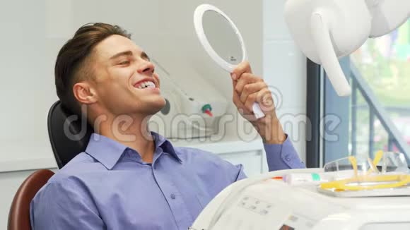英俊的年轻人在牙科诊所用镜子检查牙齿视频的预览图