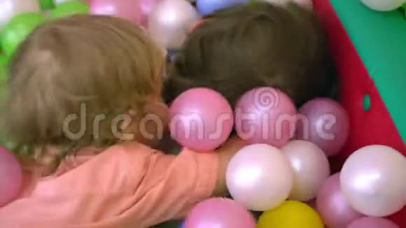 快乐的学龄前儿童在多种颜色的球池中玩幼儿园视频的预览图