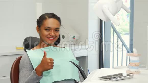 年轻女子微笑着竖起大拇指等待牙科检查视频的预览图