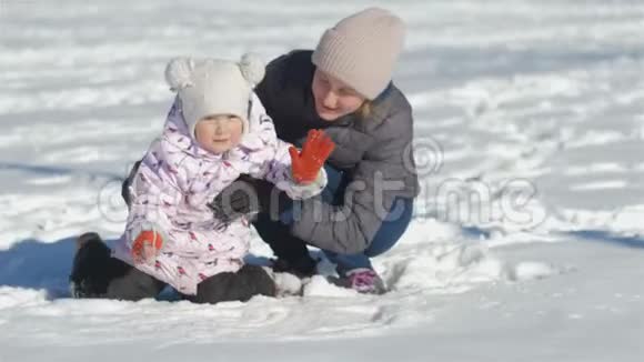 妈妈和她可爱的女儿玩了雪球后在雪地里坐了下来聊了一会儿拥抱了很久视频的预览图