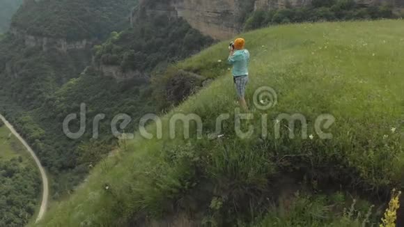 这位戴着眼镜和帽子的女摄影师在靠近高原边缘的dslr相机上拍照视频的预览图