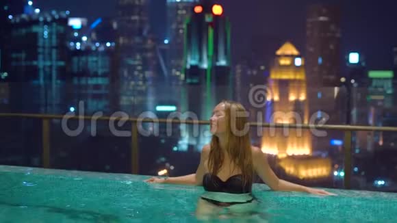美丽的年轻女子在屋顶的游泳池里玩得很开心可以看到摩天大楼亚洲概念旅行视频的预览图