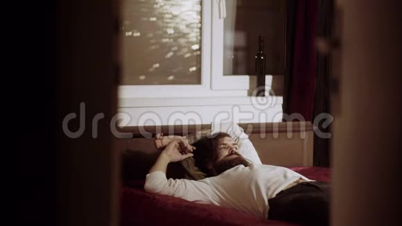 疲惫的男人躺在房间的床上视频的预览图
