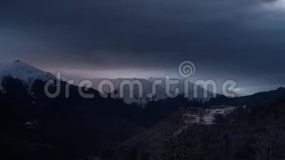 冬季山脉景观中戏剧性天空的时间推移乌云和阴影山里的房子视频的预览图