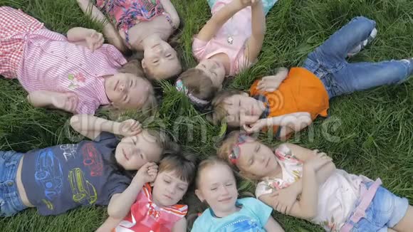 一群幼儿园的孩子躺在公园的草地上微笑着放松视频的预览图