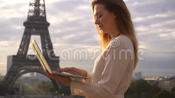成功的女性浏览笔记本电脑与埃菲尔铁塔背景和看相机视频的预览图